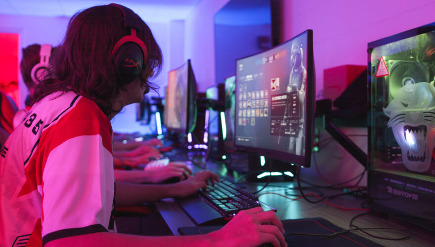 student with headphones on playing video games on computer