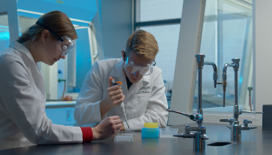 two students in science lab with eyedroppers