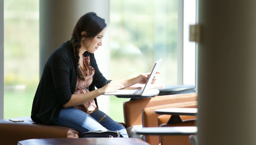 student on laptop studying in library