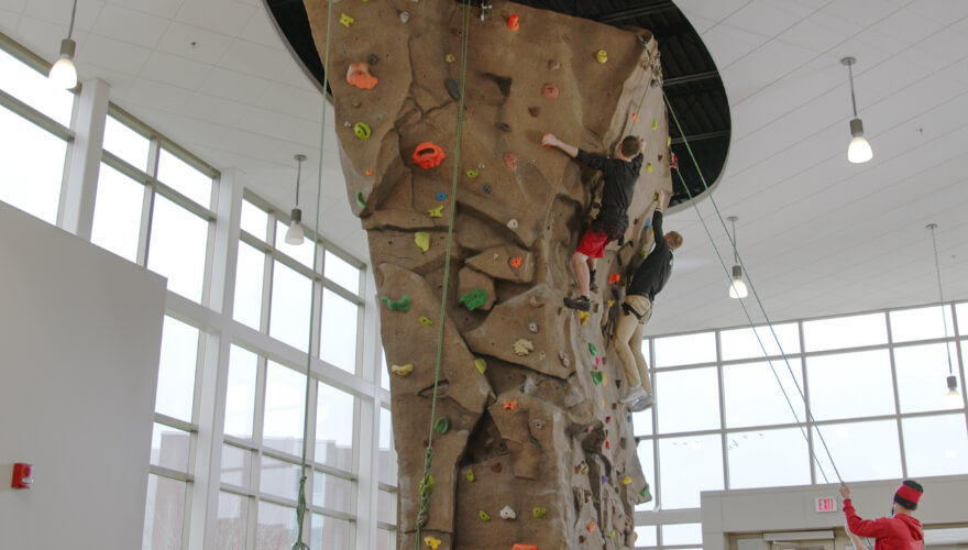 two students rock climbing on rock wall