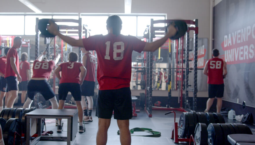 students in weight room lifting dumbbells