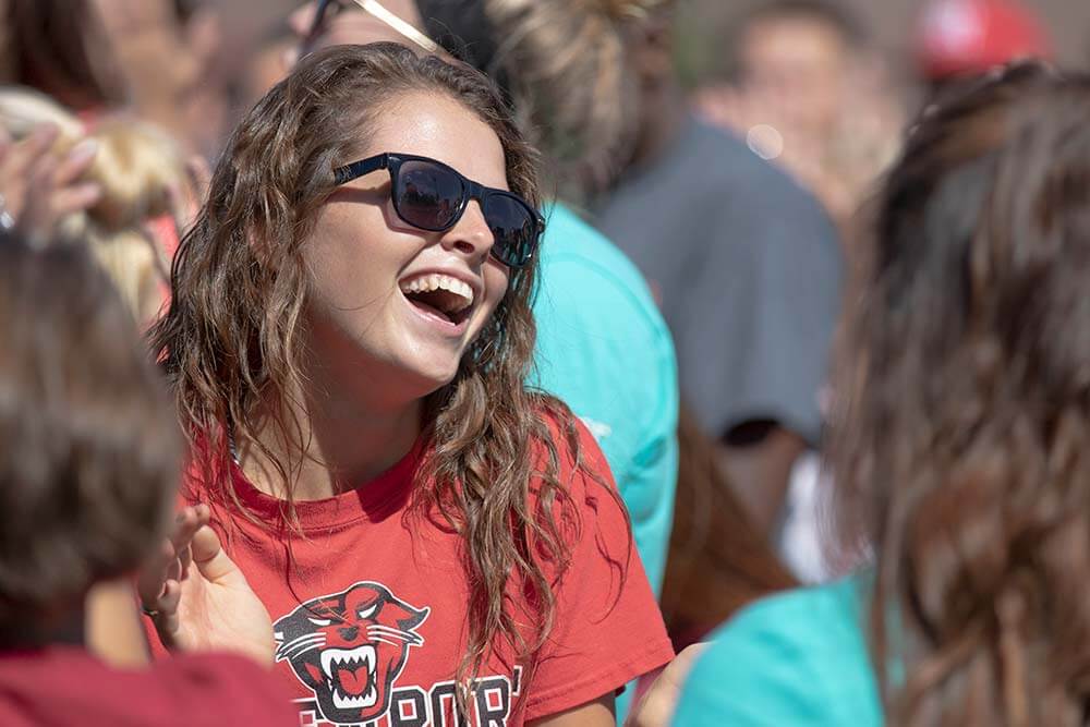 A female student in a crowd, laughing
