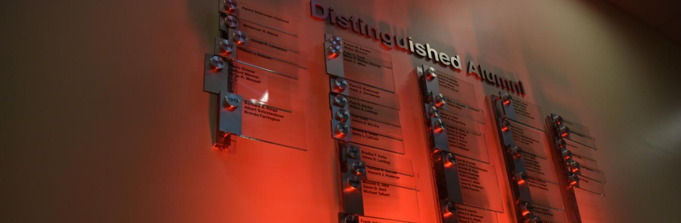 alumni names on plaques on red wall