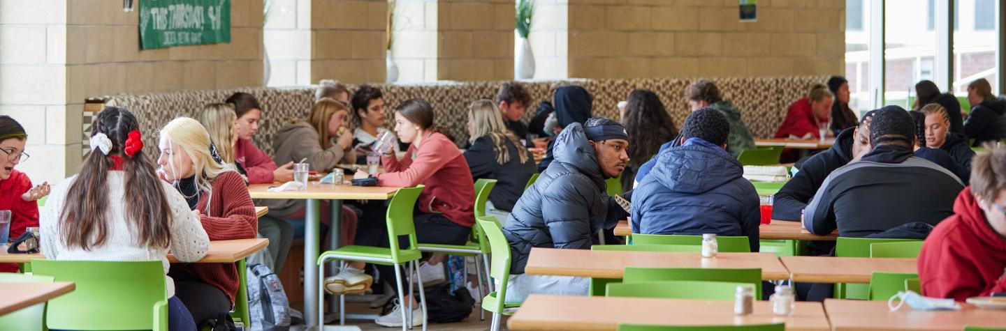 Students in the cafeteria eating lunch at tables 