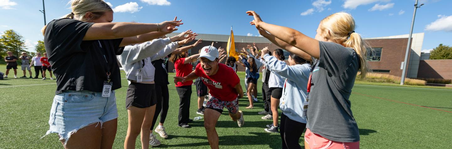 Students outside making a tunnel and a male student running through it