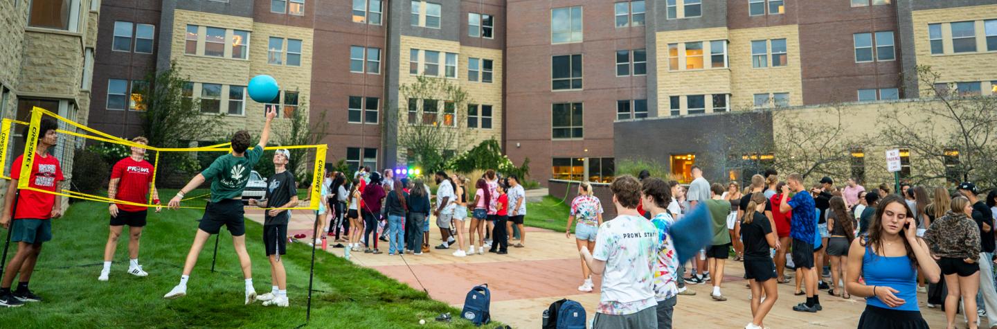 Students playing volleyball and hanging outside of South Hall