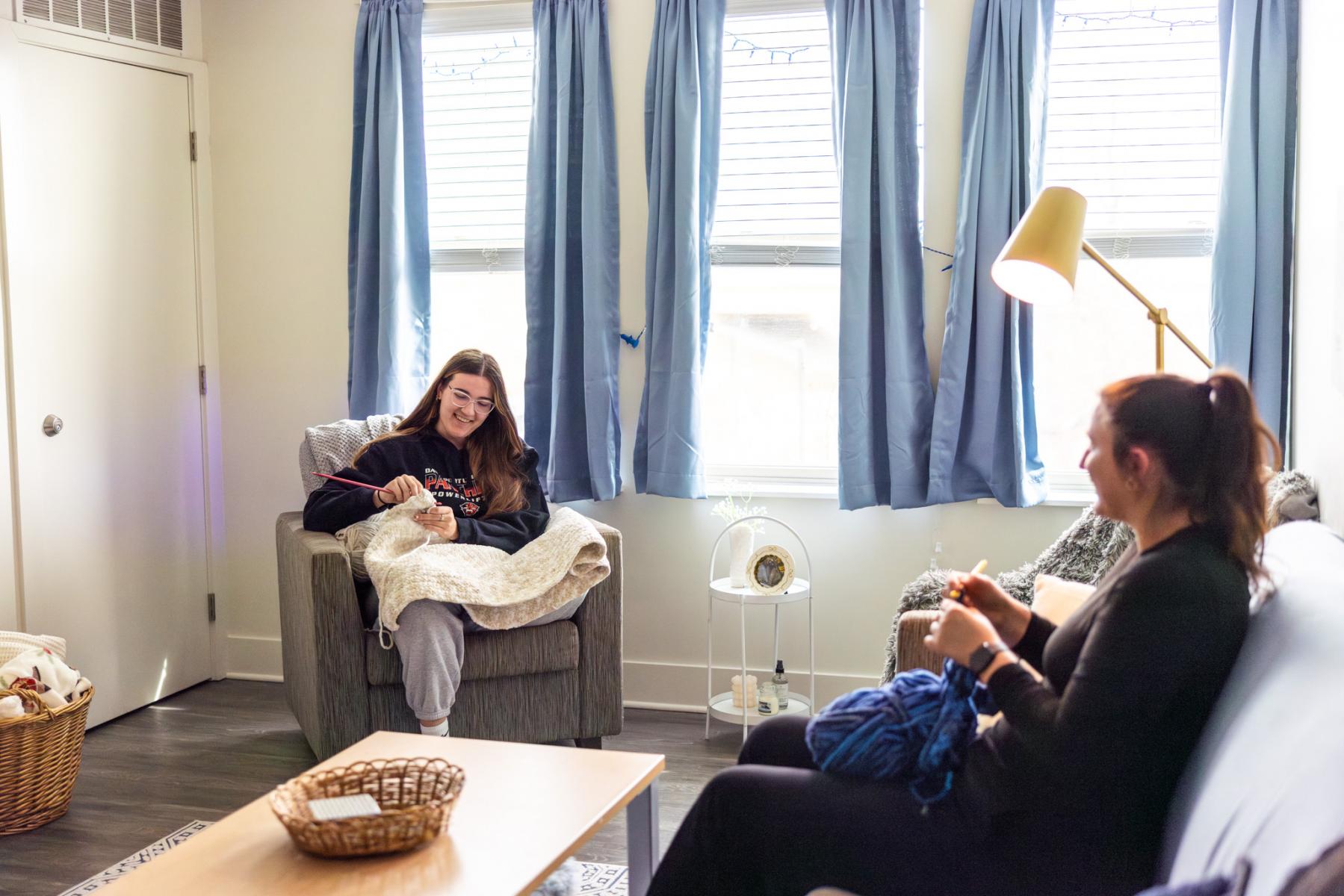 Two students knitting in their living room at Panther Ridge