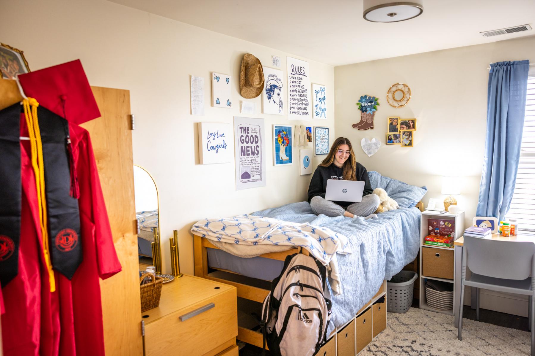 Female student sitting on her bed with her laptop in her Panther Ridge apartment