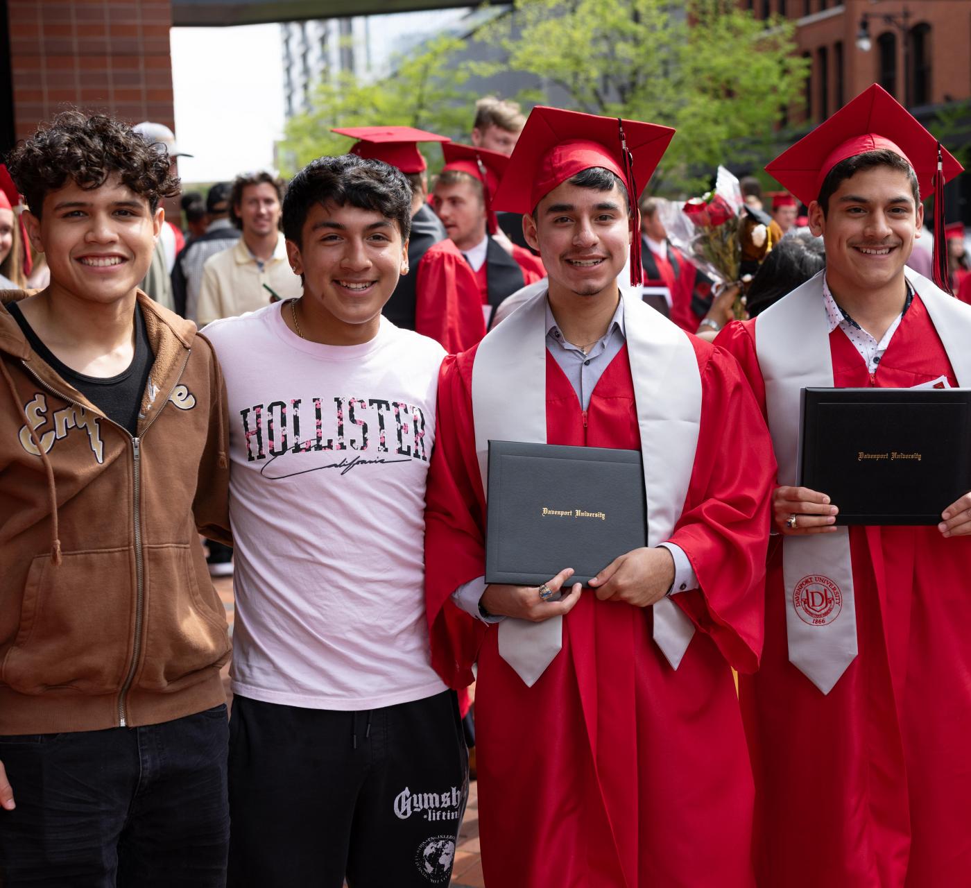 Four male Casa Latina students, two of them dressed in a cap and gown from Commencement