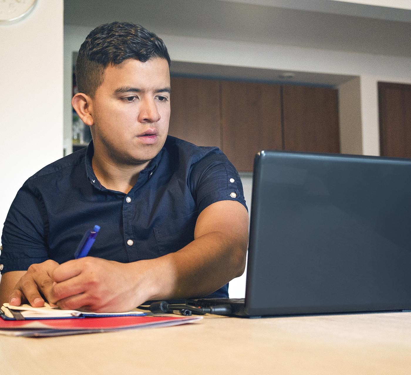 Adult male on his laptop taking notes and studying