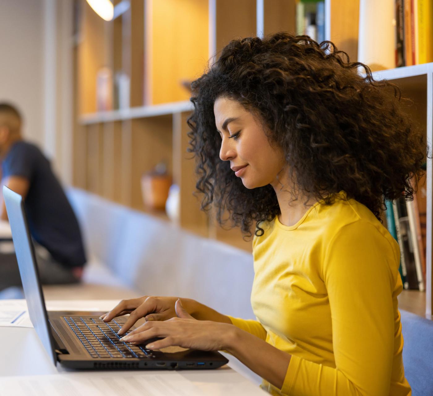 Adult female in a library studying on her laptop