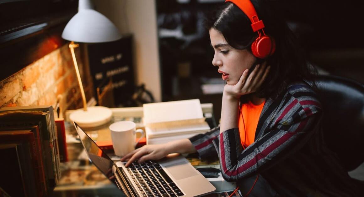Young woman with red headphones looking at laptop