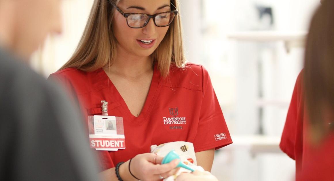 Female student in red Davenport nursing uniform