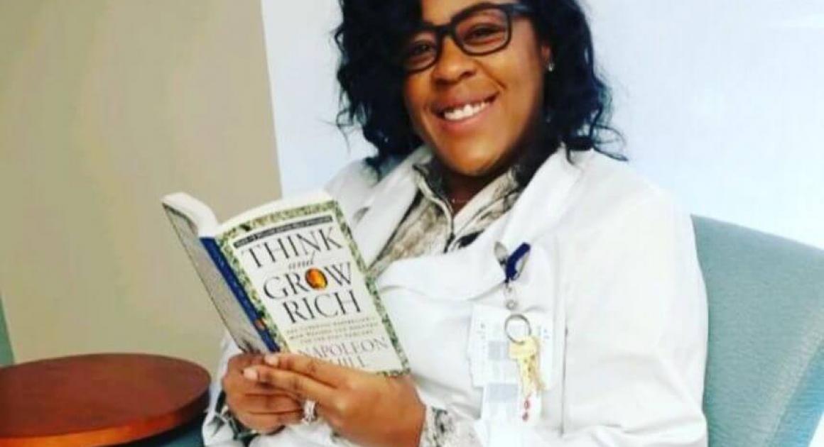 Davenport alum Kenyatta Legette smiling while holding a book