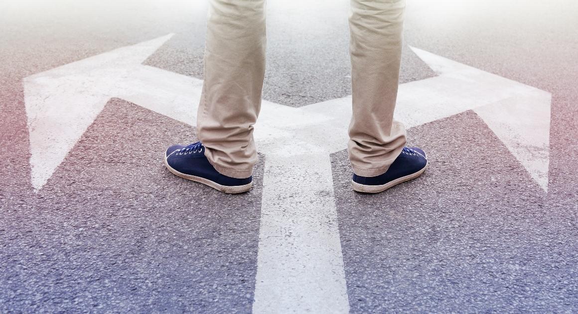 Feet standing on painted arrows pointing two different directions