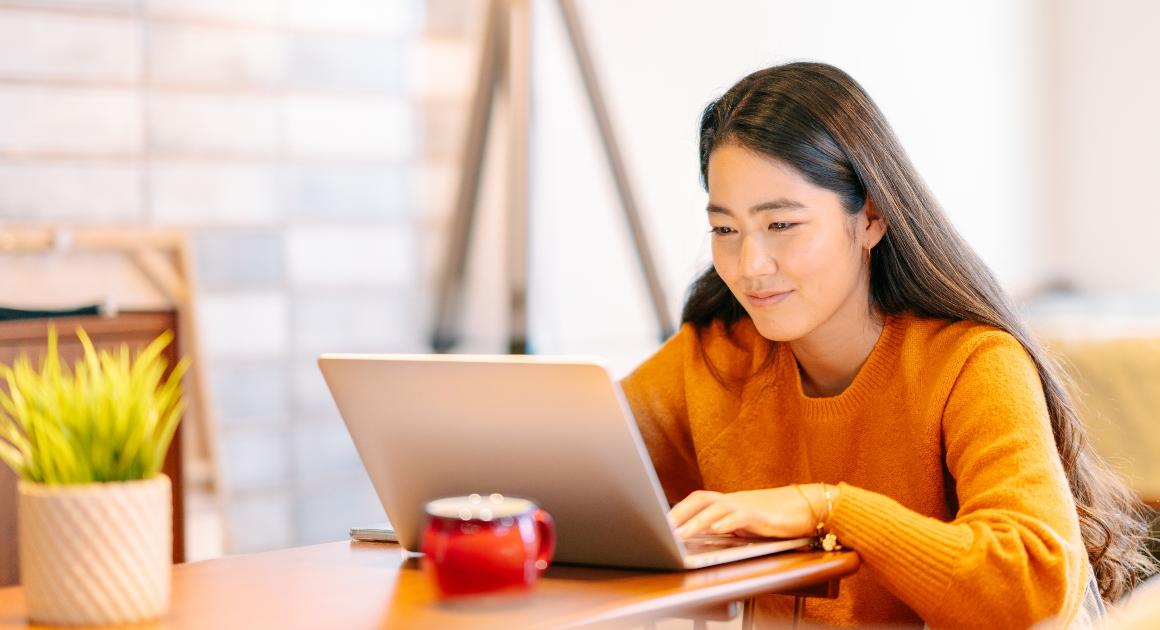 Smiling female student looking at a laptop