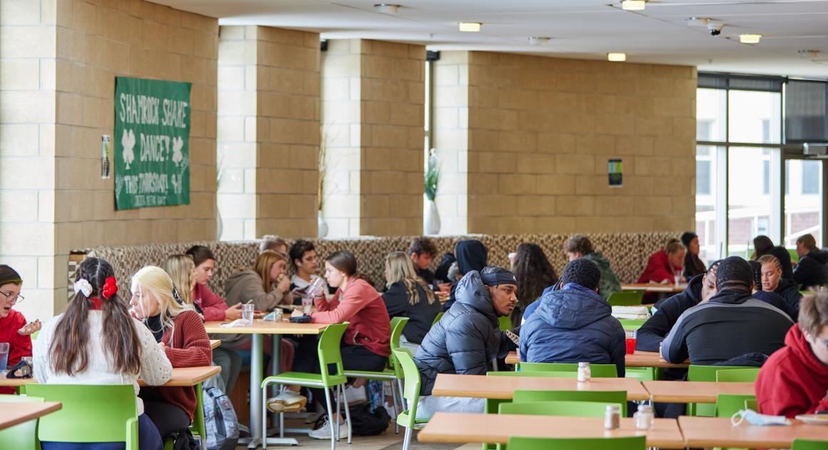 Students in the cafeteria eating lunch at tables 