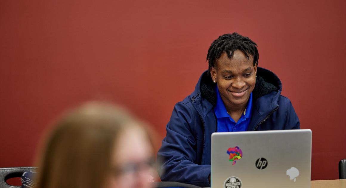 Young male student in a classroom on his computer
